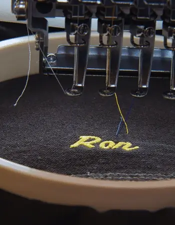 A close-up view of The Apparel Artist's high quality custom embroidery process, showcasing a vibrant design meticulously stitched onto a fabric.