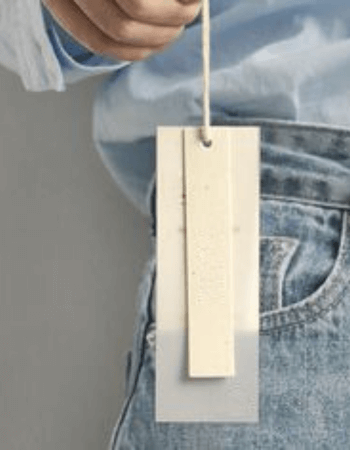 Female hand holding a custom hangtag, showcasing the power of tangible brand communication