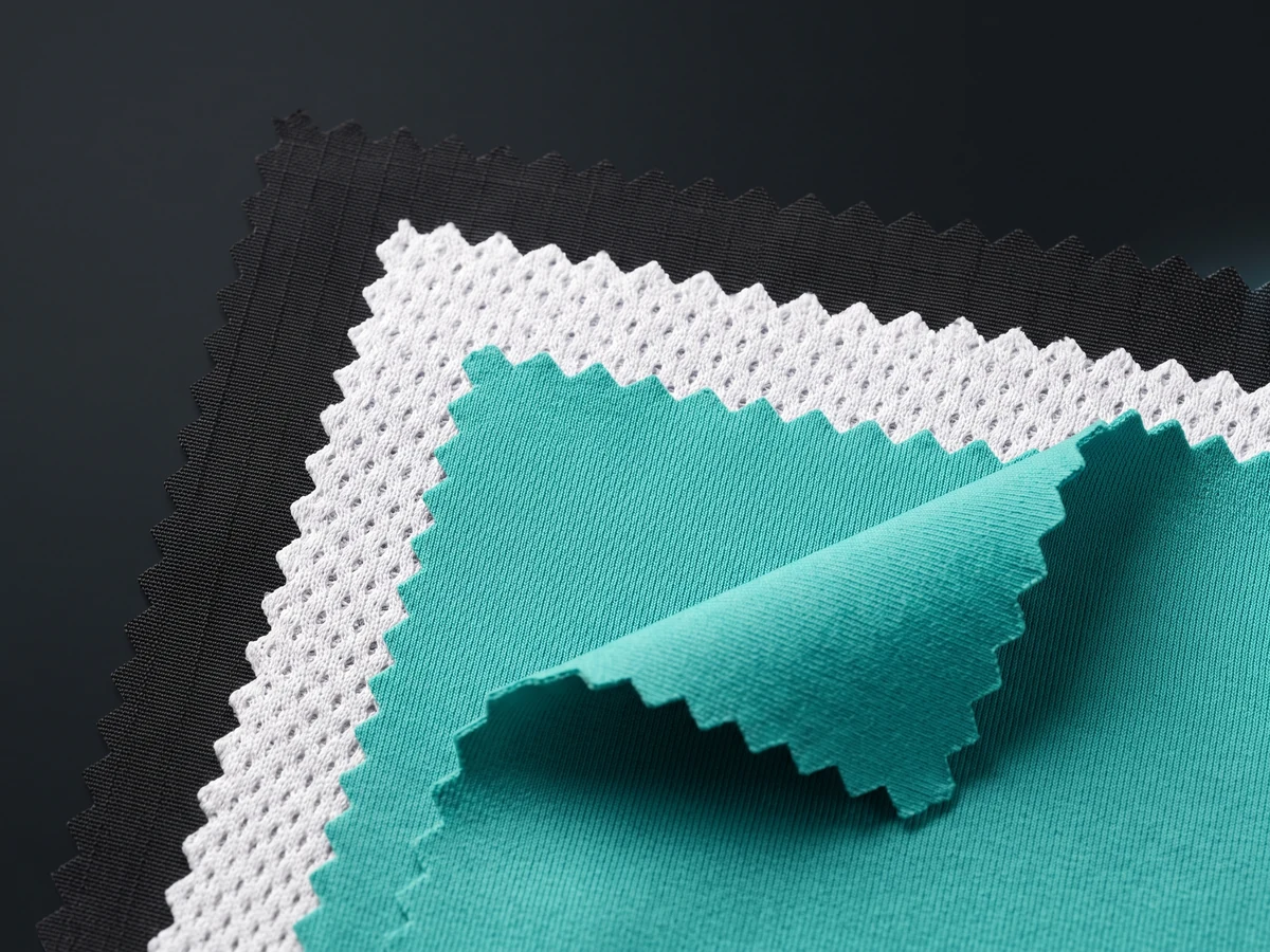 Close-up of gym shorts fabrics — woven shell, birdseye mesh and four-way stretch knit swatches
