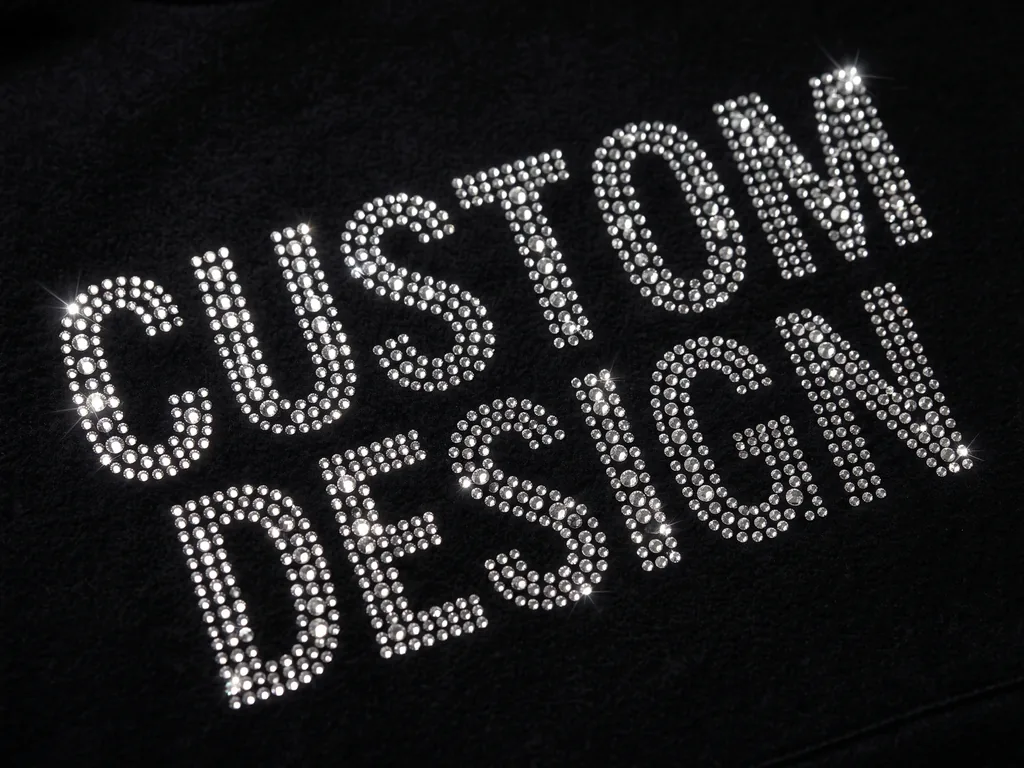 Close-up of a CUSTOM DESIGN crystal logo and lettering set in hotfix rhinestones on dark fabric